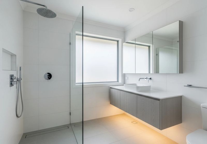 Completed modern bathroom renovation Inner West Sydney — white tiles, chrome fixtures, frameless glass shower
