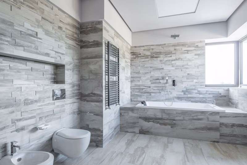 A spacious and stylish bathroom featuring modern design elements like a sleek bathtub and stone tiles.