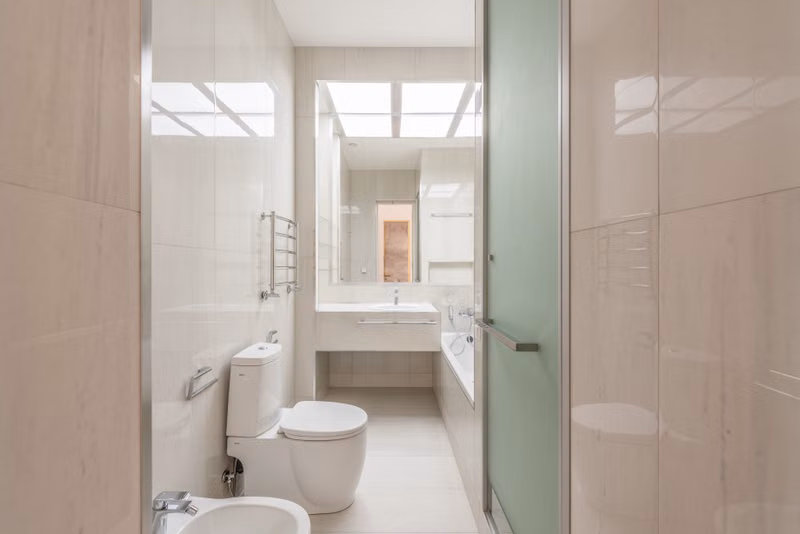 A spacious, contemporary bathroom featuring a skylight, pristine fixtures, and modern design elements.